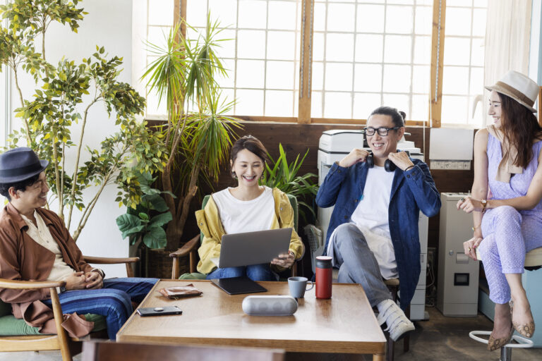 Group of young Japanese professionals working on laptop computers in a co-working space.