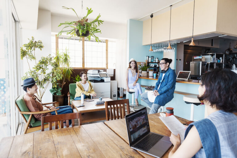 Group of young Japanese professionals working on laptop computers in a co-working space.